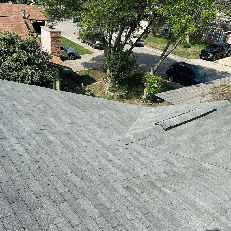 Finished gray shingle roof with a ridge cap, looking over a tree-lined street