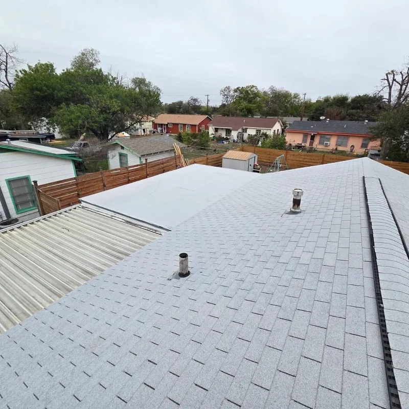 Finished light gray shingle roof with a ridge vent and pipe vents